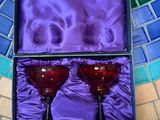 une paire de verres à vin rouge dans une boîte violette, posée sur un sol carrelé