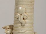 a white vase with a bird on it and a bird sitting on top of it