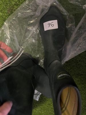 a person sitting on the grass with a pair of black rain boots