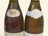 two bottles of wine sitting next to each other on a white surface