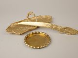 a gold plate with a feather on it next to a bottle opener