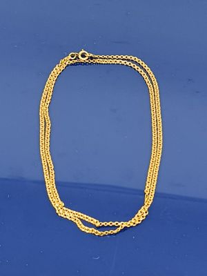 un gros plan d'un collier en or posé sur une surface bleue