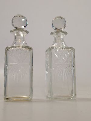 two small glass bottles sitting next to each other on a table