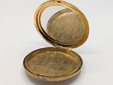 a small gold pocket watch with a mirror on it