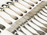 a lot of silver spoons and forks laid out on a table