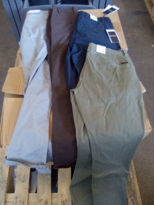 Plusieurs paires de pantalons sont empilées sur une palette dans un entrepôt