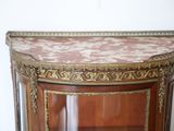 a corner cabinet with a marble top and a glass door