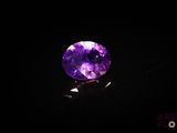 a close up of a purple stone on a black surface