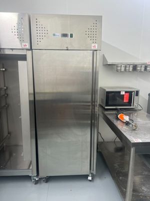 a stainless steel refrigerator in a kitchen with a microwave on the counter