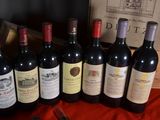 several bottles of wine are lined up on a red cloth