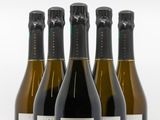 quatre bouteilles de vin sont alignées sur une surface blanche