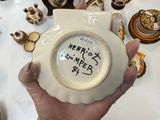 a person holding a white bowl with writing on it