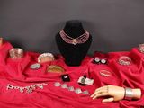un mannequin et des bijoux posés sur un tissu rouge