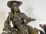 bronze statue of a woman sitting on a rock with a dog