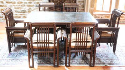 une table et des chaises dans une pièce avec un mur en pierre en arrière-plan