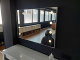 a mirror on the wall above a vanity with lights on