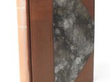 an old book sitting on top of a white table next to a white wall