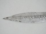 a silver spoon with a design on it on a white surface