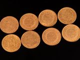 six pièces d'or sont disposées en ligne sur une surface noire