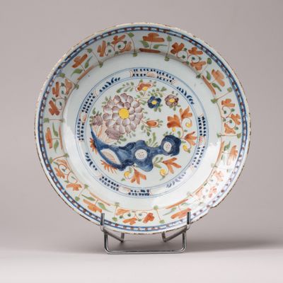 une assiette ornée d'un motif floral, posée sur un socle