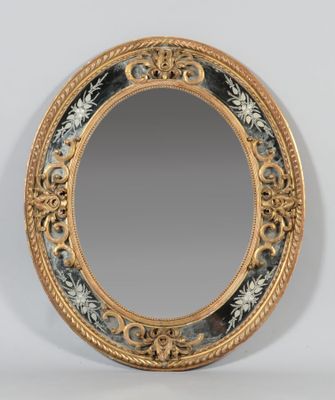 an oval mirror with a gold frame and a floral design