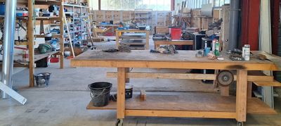 un établi au milieu d'un bâtiment, sur lequel sont posés des outils