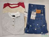 deux paires de jeans et un t-shirt posés sur une étagère