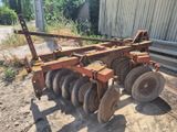 un gros plan sur une charrue de tracteur posée au milieu d'un champ de terre battue