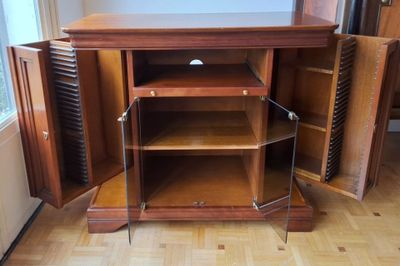 a wooden cabinet with a door open on a hard wood floor
