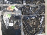 trois paires de t-shirts noirs dans des sacs en plastique posés sur une table