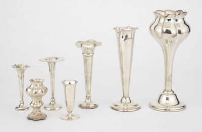 five silver vases and a candle holder on a table