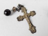 a close up of a cross and a bead on a white surface