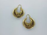 une paire de boucles d'oreilles dorées posées sur une surface blanche