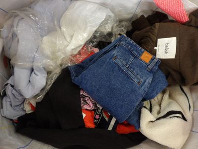 un tas de vêtements dans un sac en plastique posé sur un lit