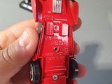 a person holding a red toy car in their hand