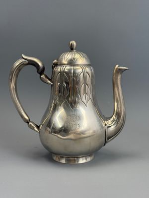 une théière en argent avec une anse, sur fond gris