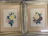 deux photos de fleurs encadrées dans des cadres dorés, posées sur une table
