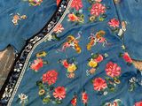 an image of a blue jacket with flowers on it on a rug