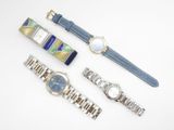 trois montres et un bracelet de montre sont posés sur une surface blanche