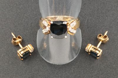 pair of black and white diamond earrings and a gold ring on a clear ring holder