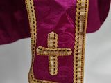 a close up of a purple dress with a gold cross on it