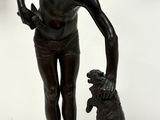 statue en bronze représentant un garçon avec un chien, posée sur un socle