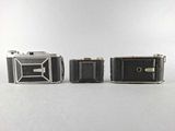 three old cameras sitting next to each other on a white surface