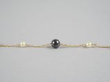 un bracelet composé d'une perle noire et d'une chaîne en or