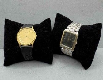 pair of two wrist watches with black velvet cases on a table