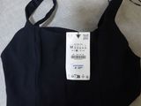 black bra top with a tag on it sitting on a bed