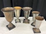 quatre vases en argent posés les uns à côté des autres sur une table