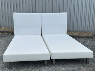 a pair of white leather chaise loungers in a parking lot