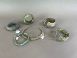 several different types of rings and bracelets are displayed on a table
