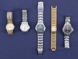Plusieurs montres sont alignées les unes à côté des autres sur une surface bleue